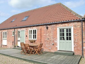 A brick building with a tiled roof, a front door, and a patio with a table and chairs. - 3 bedroom accommodation in Brandesburton, near Bridlington (Brandesburton, near Bridlington)