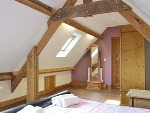 Un dormitorio con techo inclinado, tragaluz, cama con toallas, cómoda de madera y espejo.