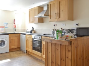 A kitchen with wooden cabinets, a washing machine, a dishwasher, an oven, and a microwave. - 3 bedroom accommodation in Brandesburton, near Bridlington (Brandesburton, near Bridlington)