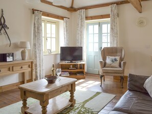 Una sala de estar con una mesa de madera, televisor, sofá y sillón.