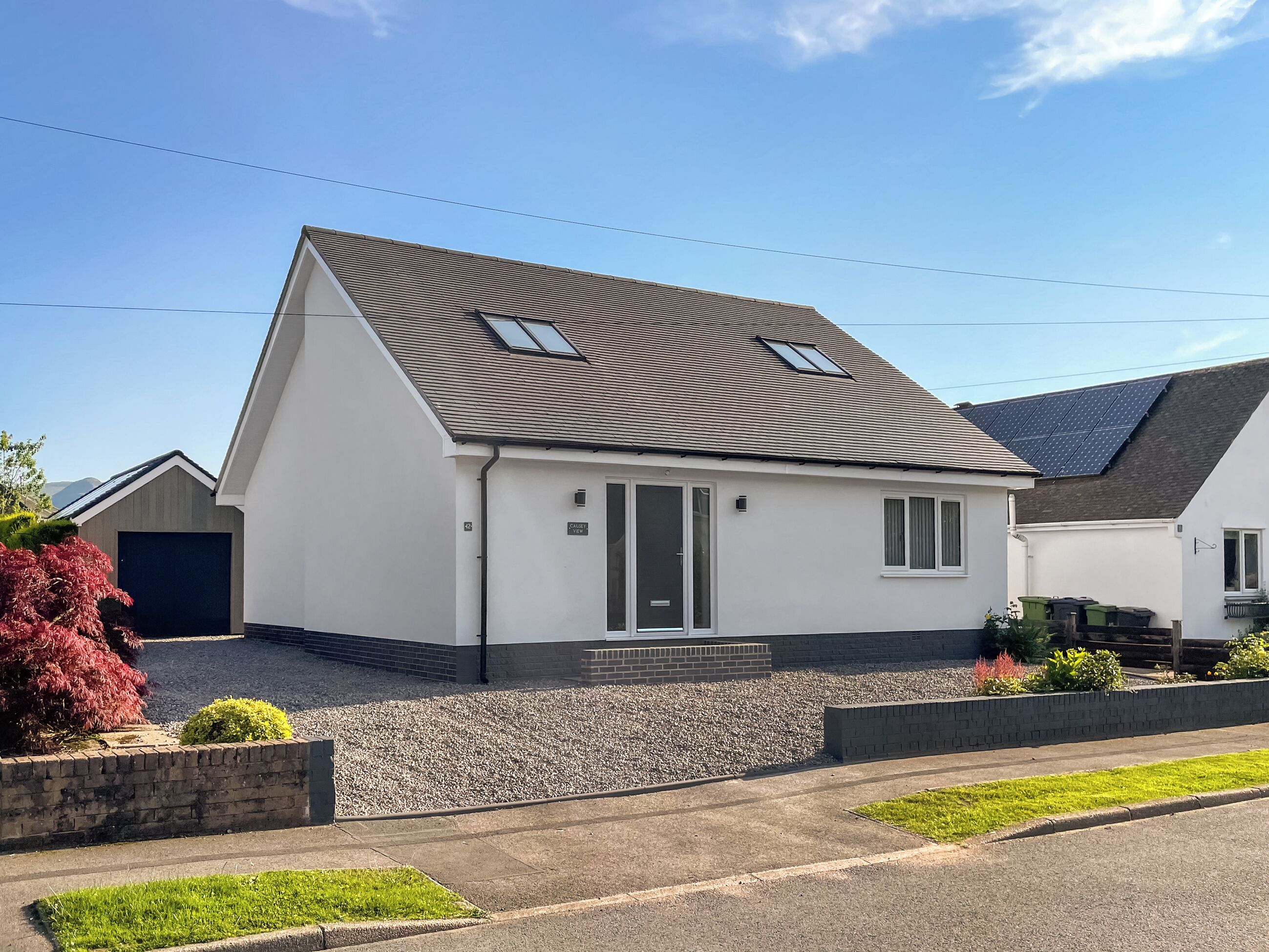A single-story house with a sloped roof, a garage, and a small garden area.