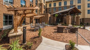 Un patio con mobiliario exterior, una pérgola y una zona cubierta.