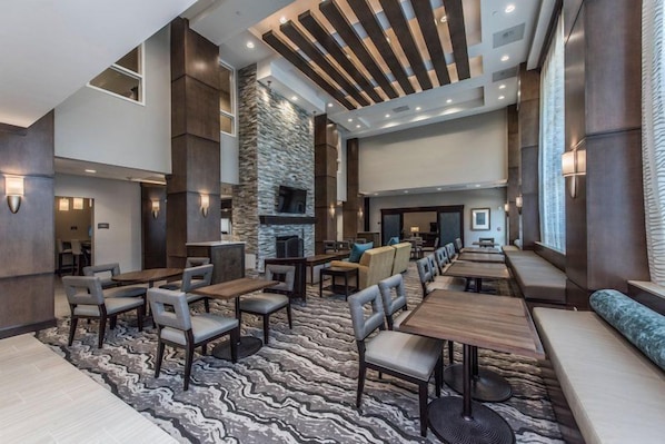 A spacious indoor area with multiple seating arrangements, a stone fireplace, and a modern ceiling design.