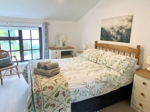 Een slaapkamer met een bed, een bureau, een stoel en een raam.