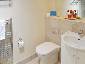 A bathroom with a toilet, sink, towel rack, and a mirror.