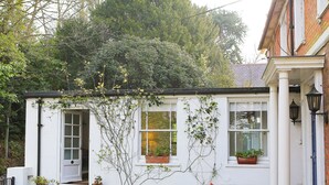 A white building with a door, windows, and potted plants. - 1 bedroom accommodation in Frant, Tunbridge Wells (Frant, Tunbridge Wells)