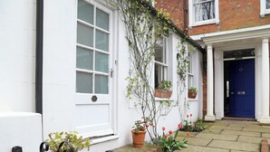 A white building with a blue door, potted plants, and a brick pathway. - 1 bedroom accommodation in Frant, Tunbridge Wells (Frant, Tunbridge Wells)