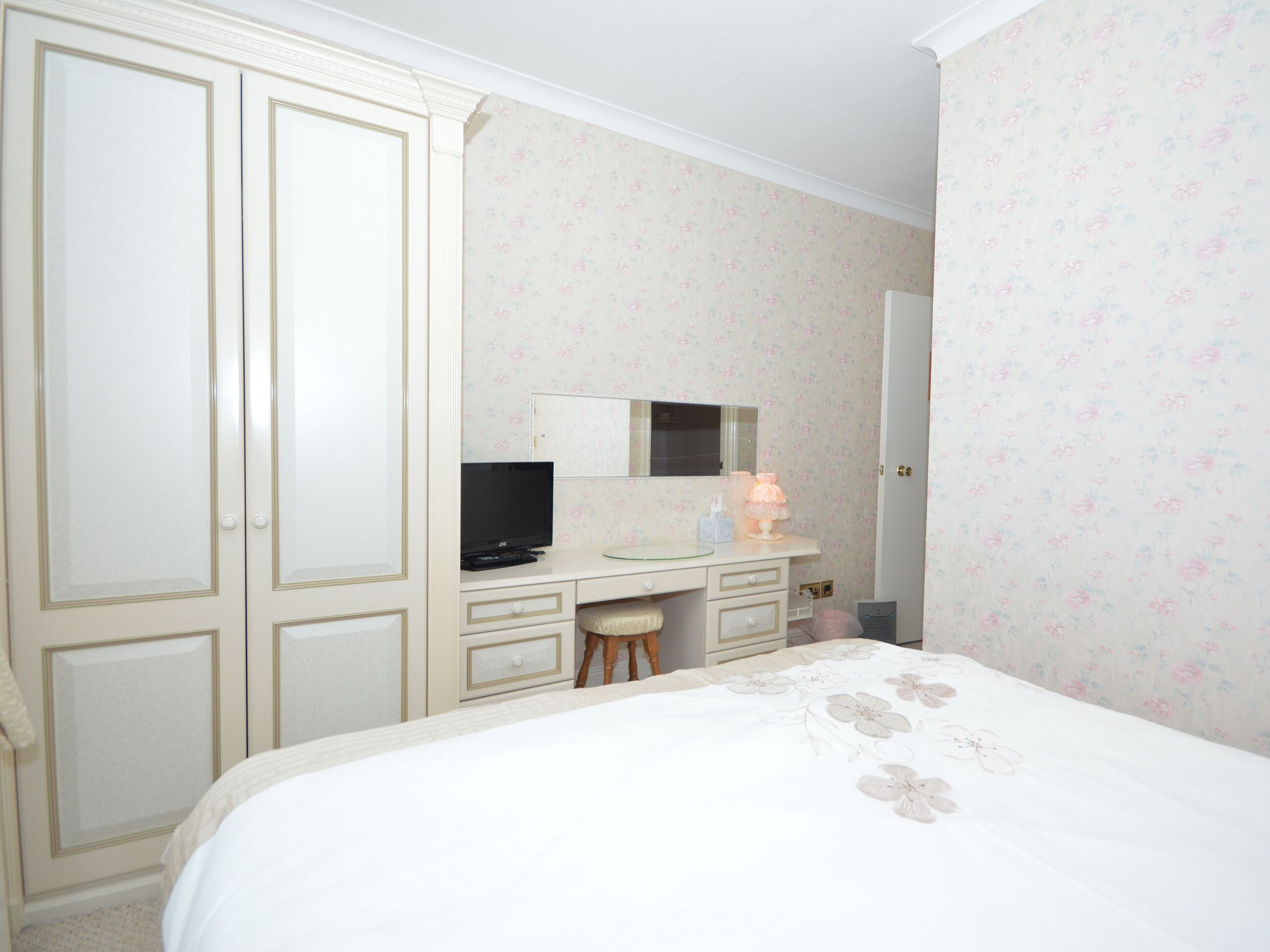 Una camera da letto con un letto, una cassettiera, una televisione e uno specchio.