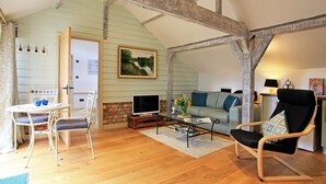 Un salon chaleureux avec un plancher en bois, un canapé, une table basse et un téléviseur.