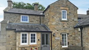 Une petite maison en pierre avec une pancarte indiquant « The Cottage ».
