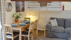 A cozy dining area with a wooden table, chairs, and a grey sofa. A ladder is leaning against the wall, and a fire extinguisher is mounted on the wall. - 0 bedroom accommodation in Brocklebank, near Caldbeck and Uldale (Brocklebank, near Caldbeck and Uldale)