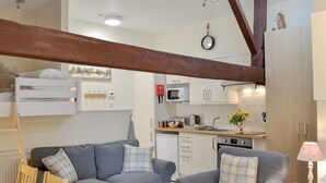 A compact living space with a grey sofa, a smaller armchair, a wooden dining table, and a kitchenette area. - 0 bedroom accommodation in Brocklebank, near Caldbeck and Uldale (Brocklebank, near Caldbeck and Uldale)