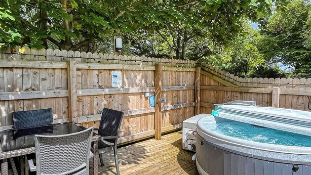 A wooden deck with a hot tub, wicker chairs, and a table. - 0 bedroom accommodation in Brocklebank, near Caldbeck and Uldale (Brocklebank, near Caldbeck and Uldale)