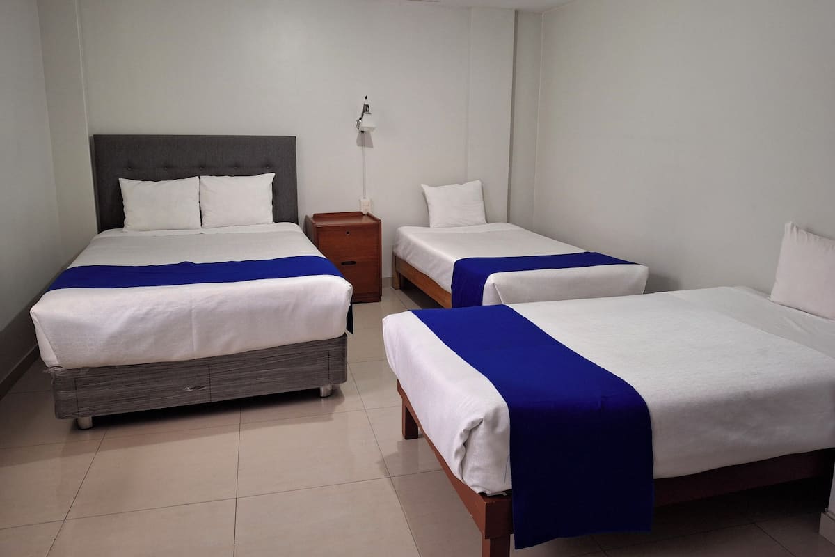 Une chambre d’hôtel avec deux lits, une table de chevet et une lampe fixée au mur.