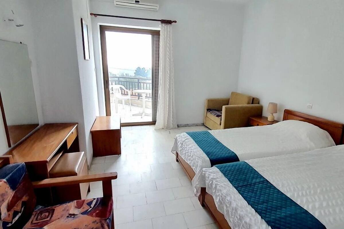 A hotel room with a bed, a desk, a chair, a sofa, and a balcony view.