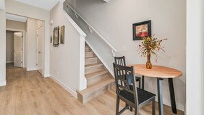 A staircase with a wooden finish, a dining table with chairs, and a vase with flowers.