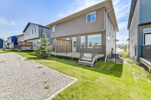 A modern two-story house with a covered porch, a small front yard, and a gravel driveway.