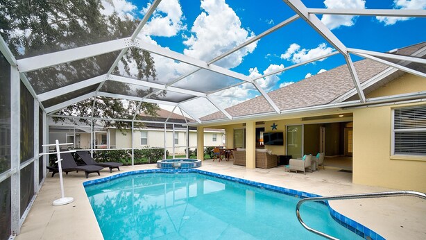 Une piscine couverte avec des chaises longues, un petit jacuzzi et un espace patio aménagé avec du mobilier d’extérieur.