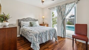 A bedroom with a bed, nightstand, lamp, and a chair.