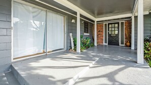 A covered porch with a concrete floor, a sliding glass door, and a brick wall.