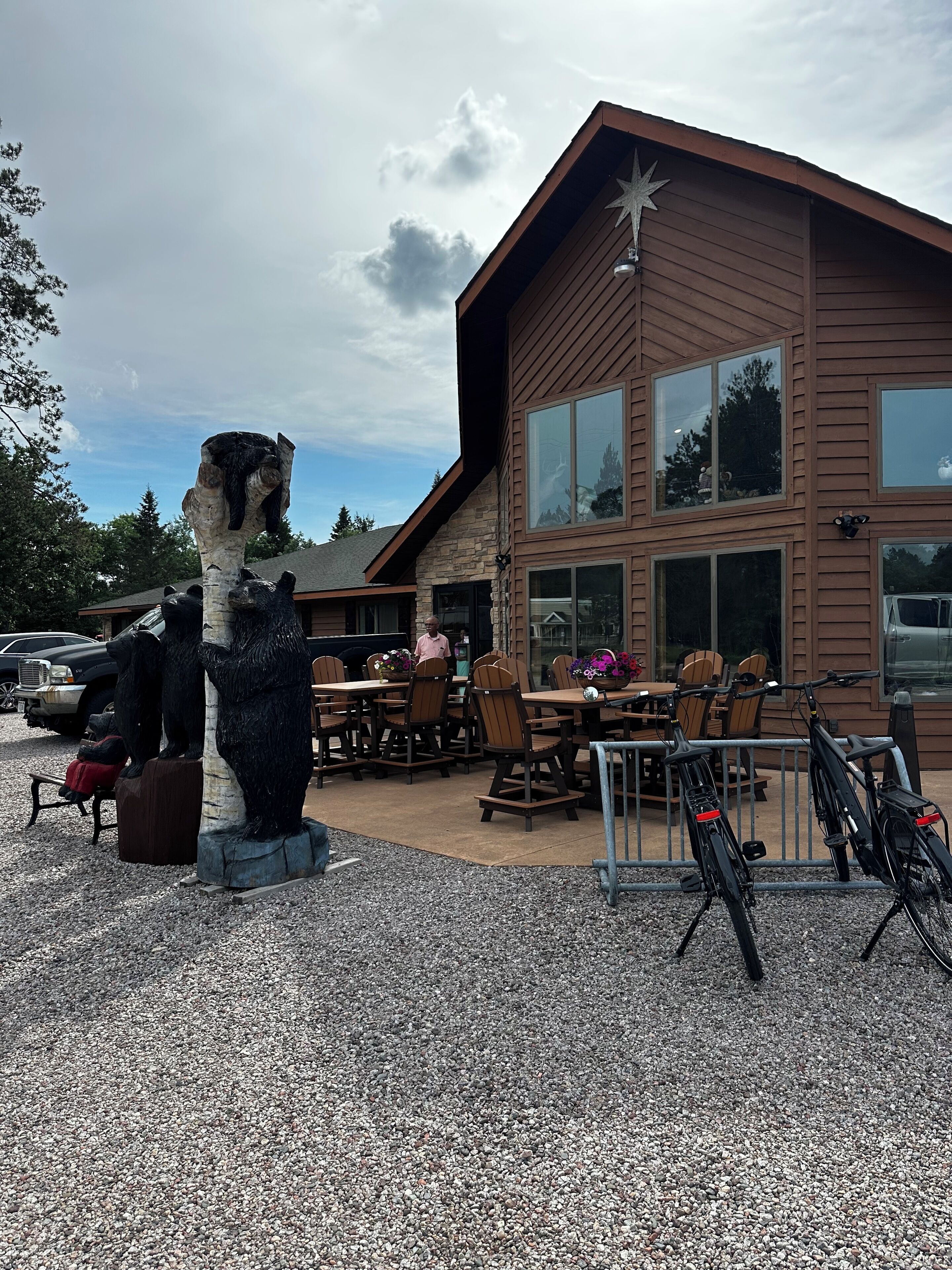 A building with a stone facade and large windows, outdoor seating, and a bear statue.
