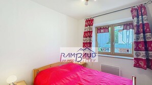 Een slaapkamer met een houten bed, een nachtkastje, een raam met gordijnen en een radiator.