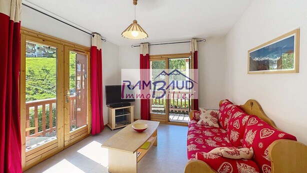Een ruime woonkamer met een bank, een salontafel en een televisie. Er is een glazen schuifdeur die leidt naar een buitenruimte.