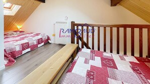 A small attic bedroom with two beds, wooden beams, and a skylight.