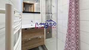 A modern bathroom with a shower, a sink, and a mirror.