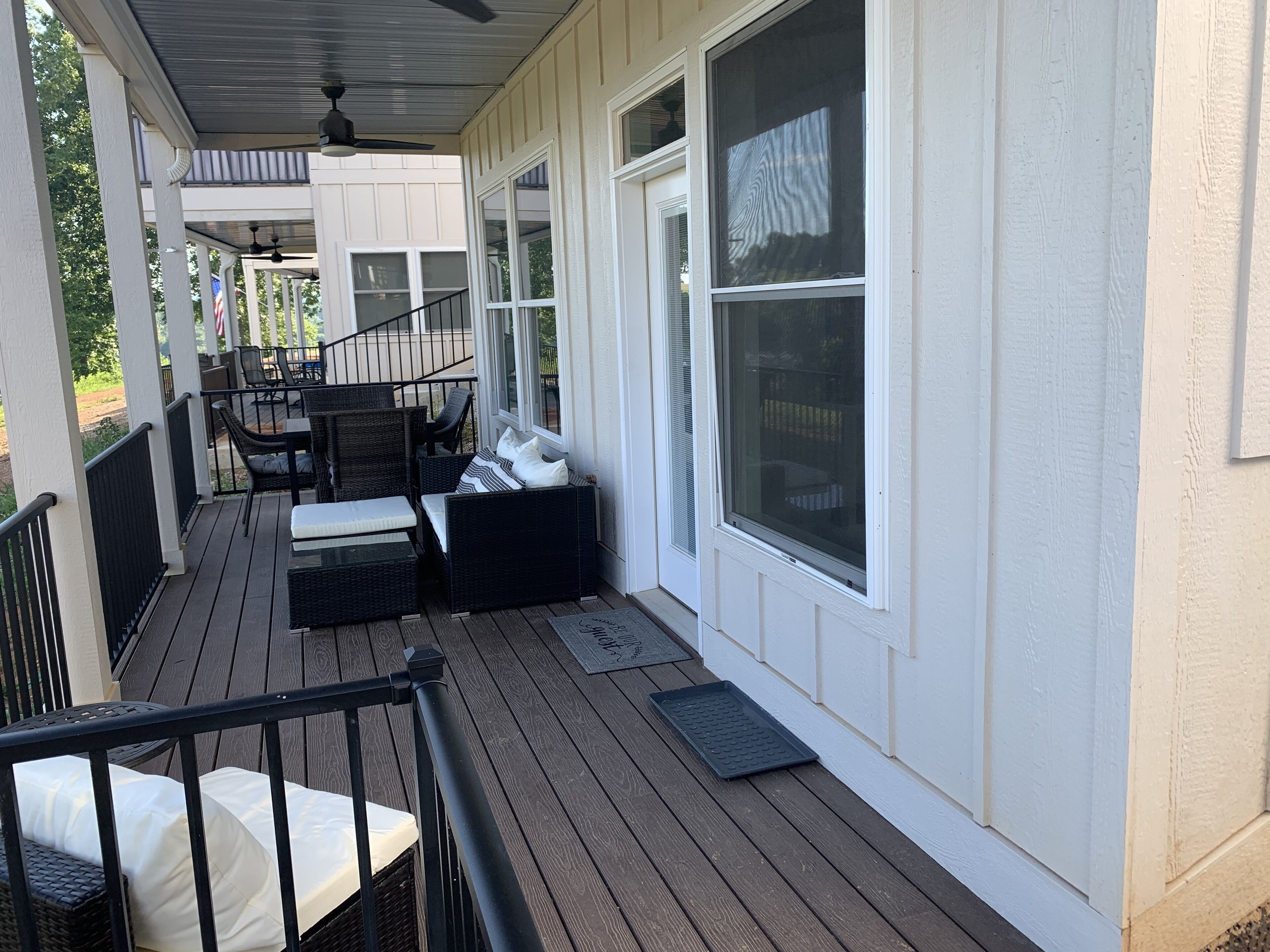 A covered porch with outdoor furniture, including a sofa and chairs, and a small table.
