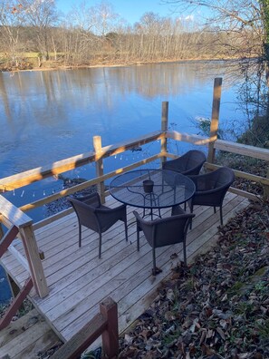Eine Holzterrasse mit Tisch und Stühlen mit Blick auf ein Gewässer.