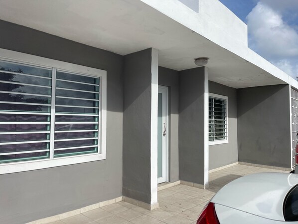 A modern building with a grey facade, white trim, and a tiled entrance.