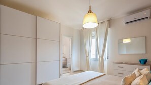 Une chambre à coucher moderne avec un lit, une commode, un miroir et un luminaire suspendu.