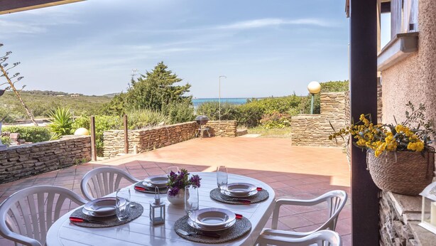 A table set for four with a view of the sea, stone walls, and greenery. - Ss-m290-cdva0at - Villino Punta Negra (Stintino)