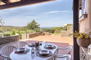 A table set for four with a view of the sea, stone walls, and greenery. - Ss-m290-cdva0at - Villino Punta Negra (Stintino)