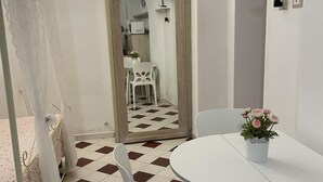 A room with a checkered floor, white walls, a round table with chairs, and a flower vase.
