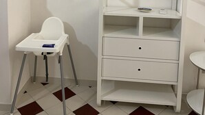 A white bathroom with a white toilet, a white sink, and a white cabinet with drawers.