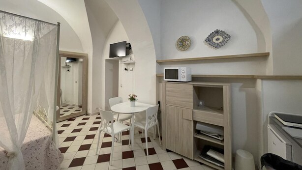 A compact kitchen with a checkered floor, a microwave, and a small dining table with chairs.