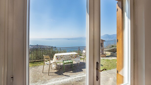 Ein Balkon mit Tisch und Stühlen, der einen herrlichen Blick auf das Meer und die Berge bietet.
