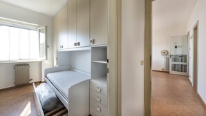 Ein Schlafzimmer mit Bett, Einbauschrank und Fenster.