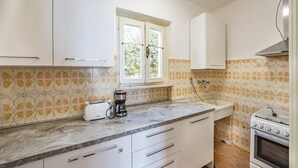 Eine Küche mit weißen Schränken, einem Fenster, einem Toaster und einem Backofen.