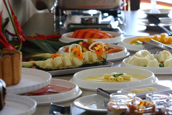 Un buffet proposant une variété de plats, notamment des fruits, des légumes et des viandes.