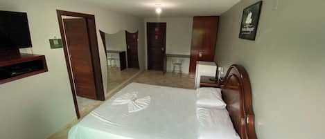 A hotel room with a bed, a television, a desk, and a chair.