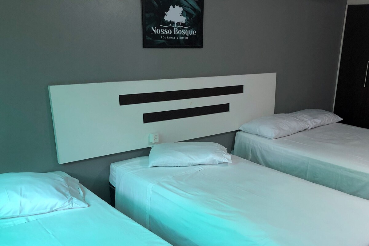 Une chambre d’hôtel avec deux lits simples, une grande tête de lit blanche et un panneau encadré accroché au mur.