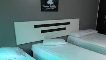 A hotel room with two single beds, a large white headboard, and a framed sign on the wall.