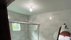 Une salle de bain avec une douche à parois de verre, des toilettes, un lavabo avec un plan de travail en granit et un miroir au-dessus du lavabo.