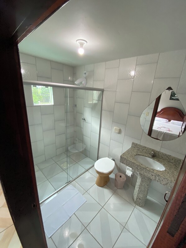 A bathroom with a glass shower enclosure, a toilet, a sink with a granite countertop, and a mirror above the sink. - HOTEL NOSSO BOSQUE (Rio do Sul)