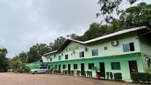 Un bâtiment à deux étages, doté d’une façade verte, de nombreuses fenêtres et d’une voiture garée devant.