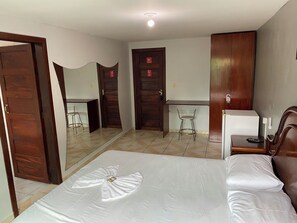 Una habitación de hotel con cama, escritorio, silla y armario.