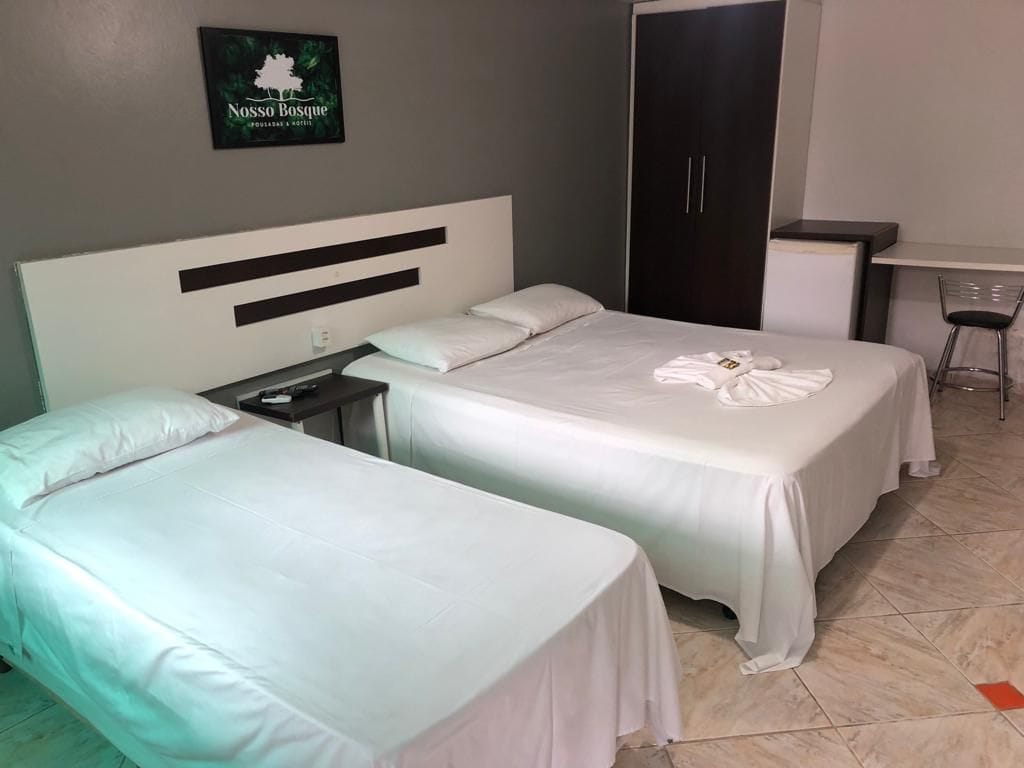 A hotel room with two beds, a desk, and a wardrobe.
